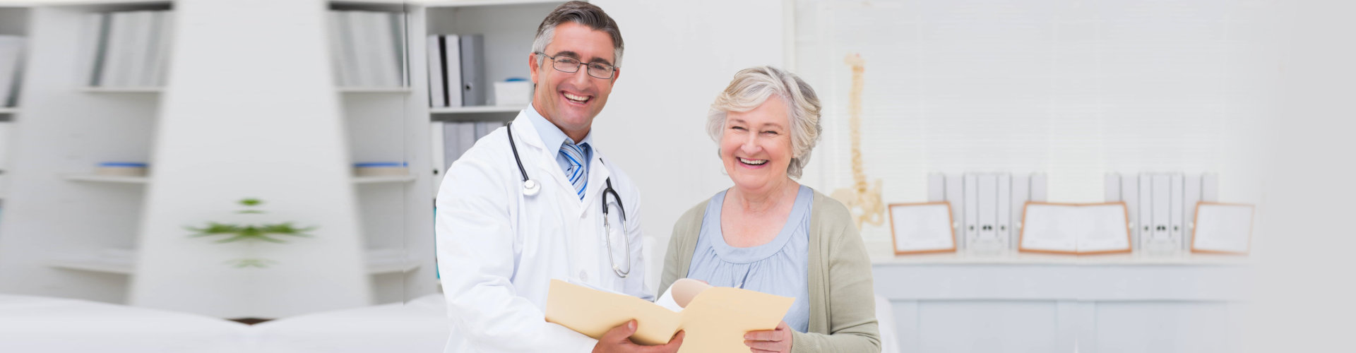 portrait of happy male doctor and female patient with reports in clinic
